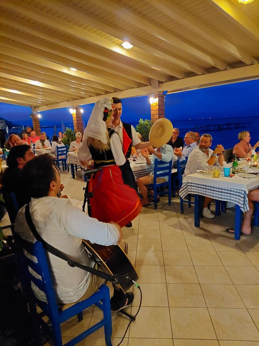 Corfiot dancers in traditional dress between the tables at dusk